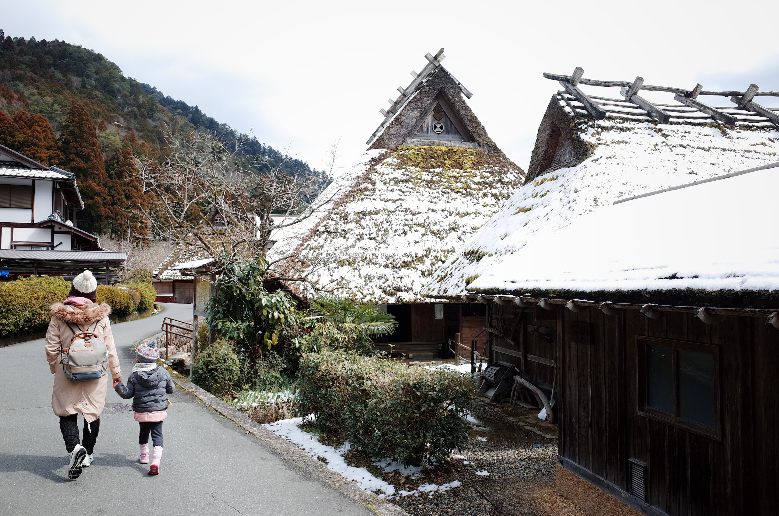 京都美山雪地裡一大一小走過茅草屋